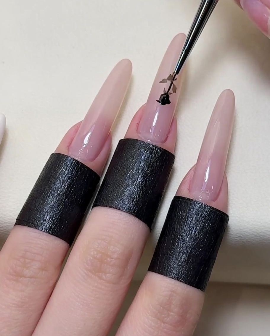 A fine-point detail brush tracing and filling in the details of the white rose design with black gel polish.