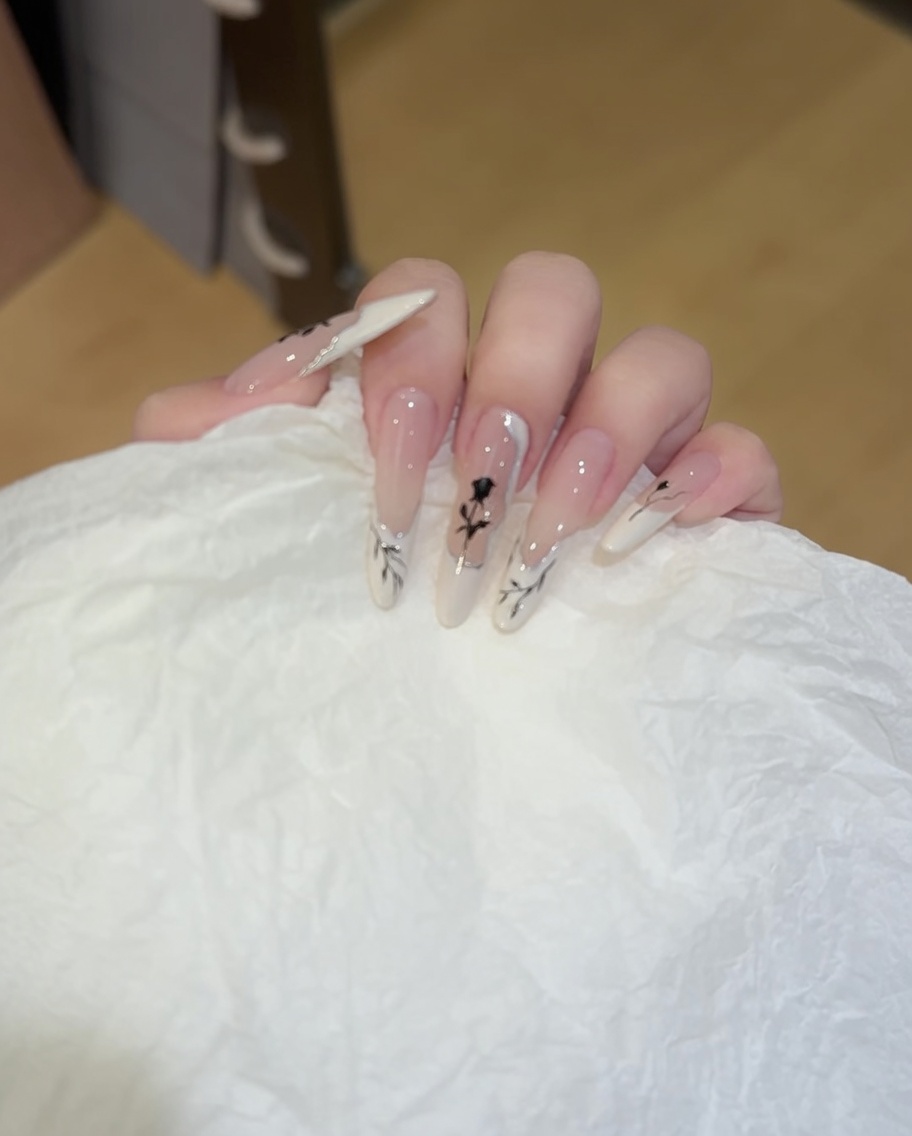 A close-up of a nail brush applying white gel polish in a wavy, irregular French tip pattern across the tip of a natural-looking nail.