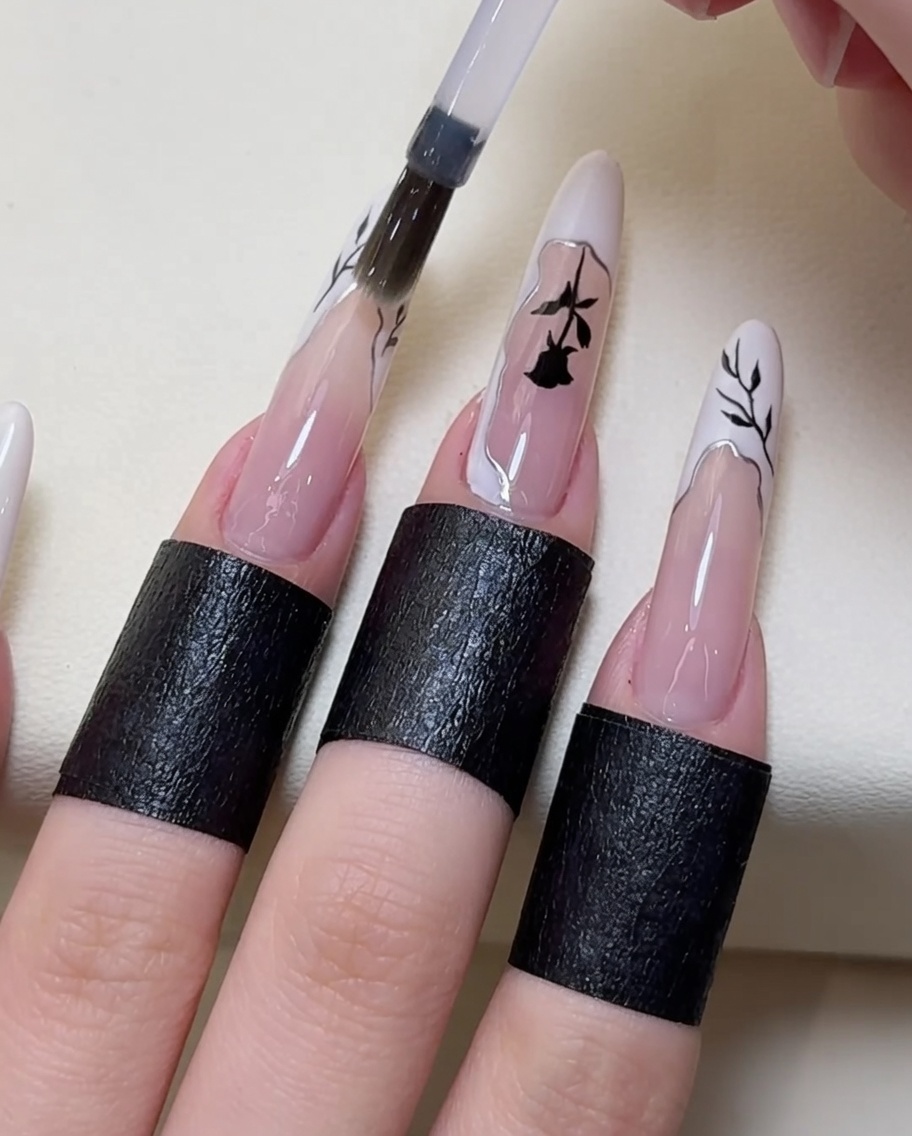 A brush applying a final layer of clear top coat over the finished nail art design.
