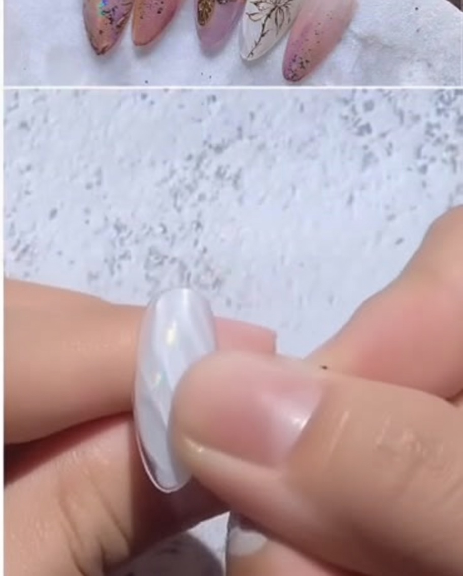 The plastic backing of a transfer foil being peeled away, revealing a shimmering finish on the nail.