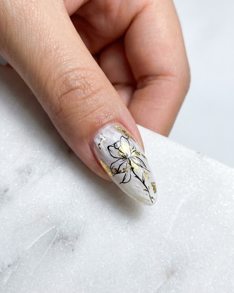 Close-up of a fine liner brush painting a curved, gold metallic petal outline on the upper left of a rose design.