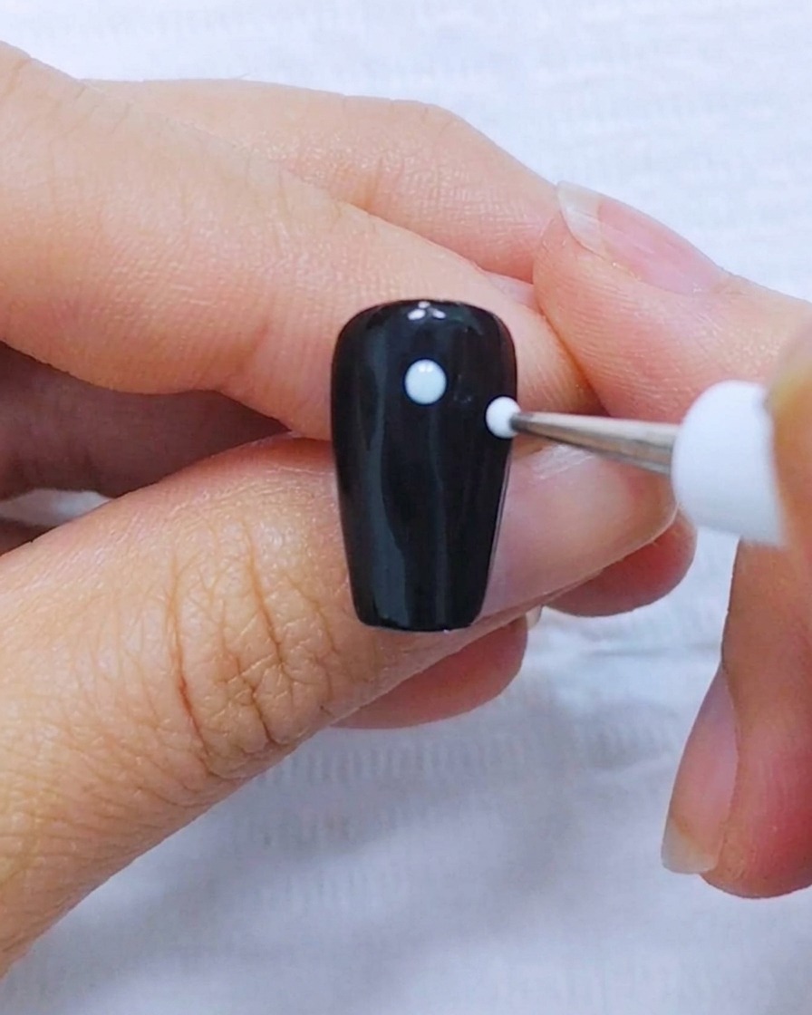A view of the five white dots arranged symmetrically on a black nail background.