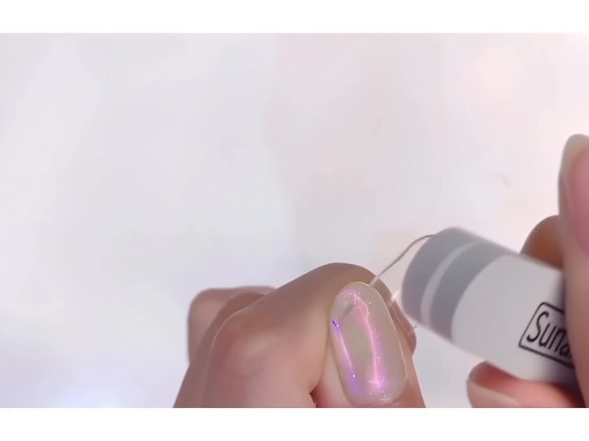 A nail file buffing the surface of a clear nail tip until it appears matte.