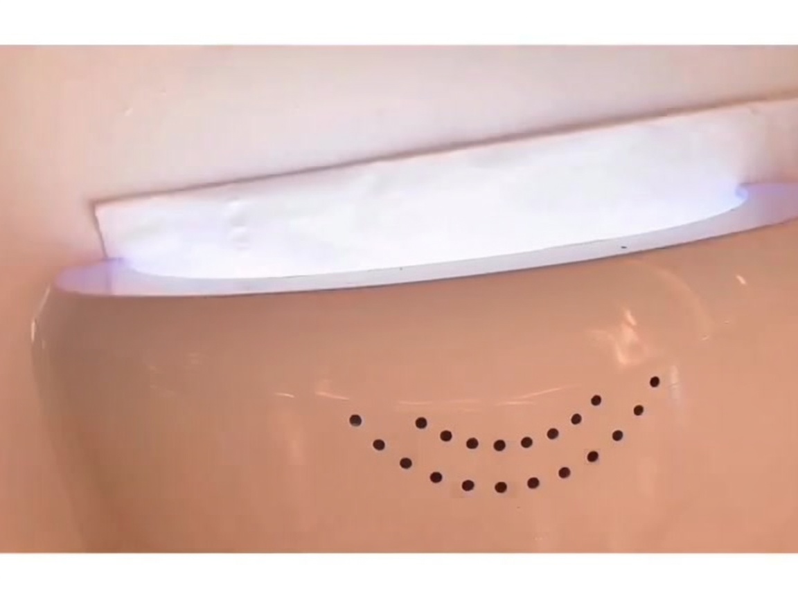 A hand placed inside an LED nail lamp with the light illuminated, curing the base coat.