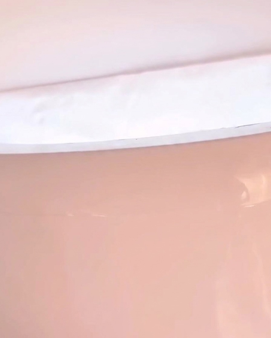A close-up of a hand resting inside an LED nail lamp with pinkish light emitting from within.