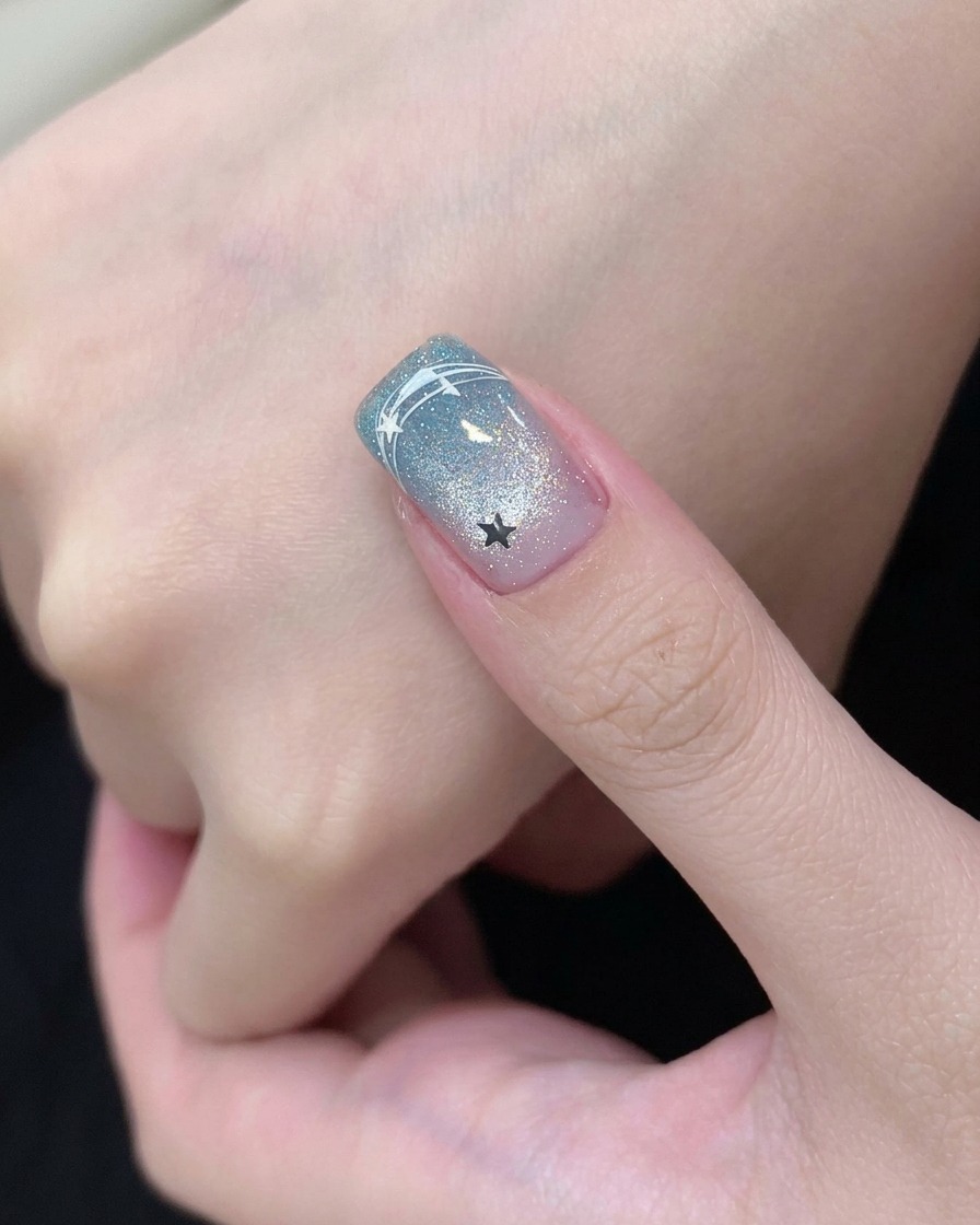 A brush applying clear base coat onto a prepped fingernail.
