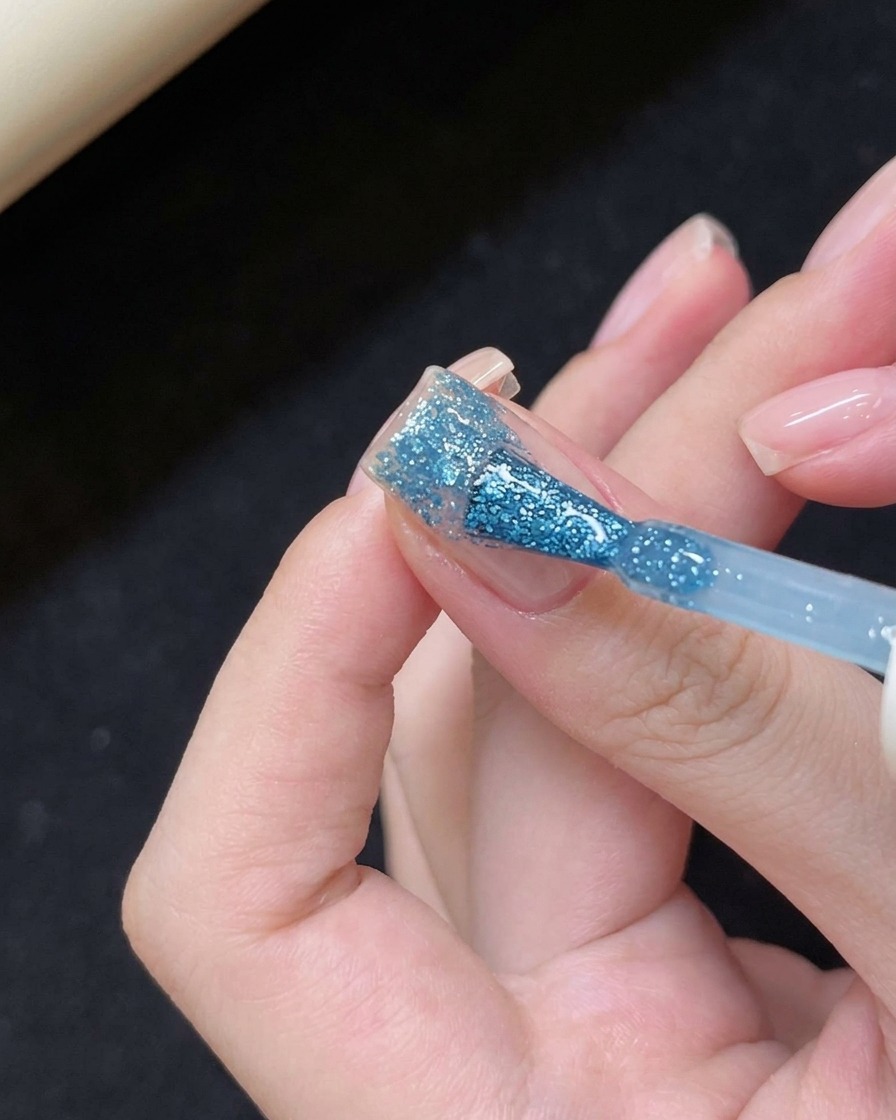 Applying blue-tinted gel to the tip of the nail.
