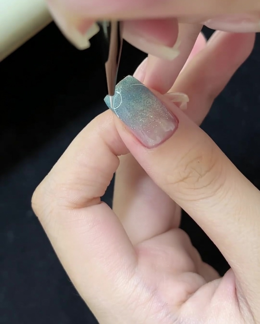 Using a thin liner brush to draw fine white lines on the nail surface.
