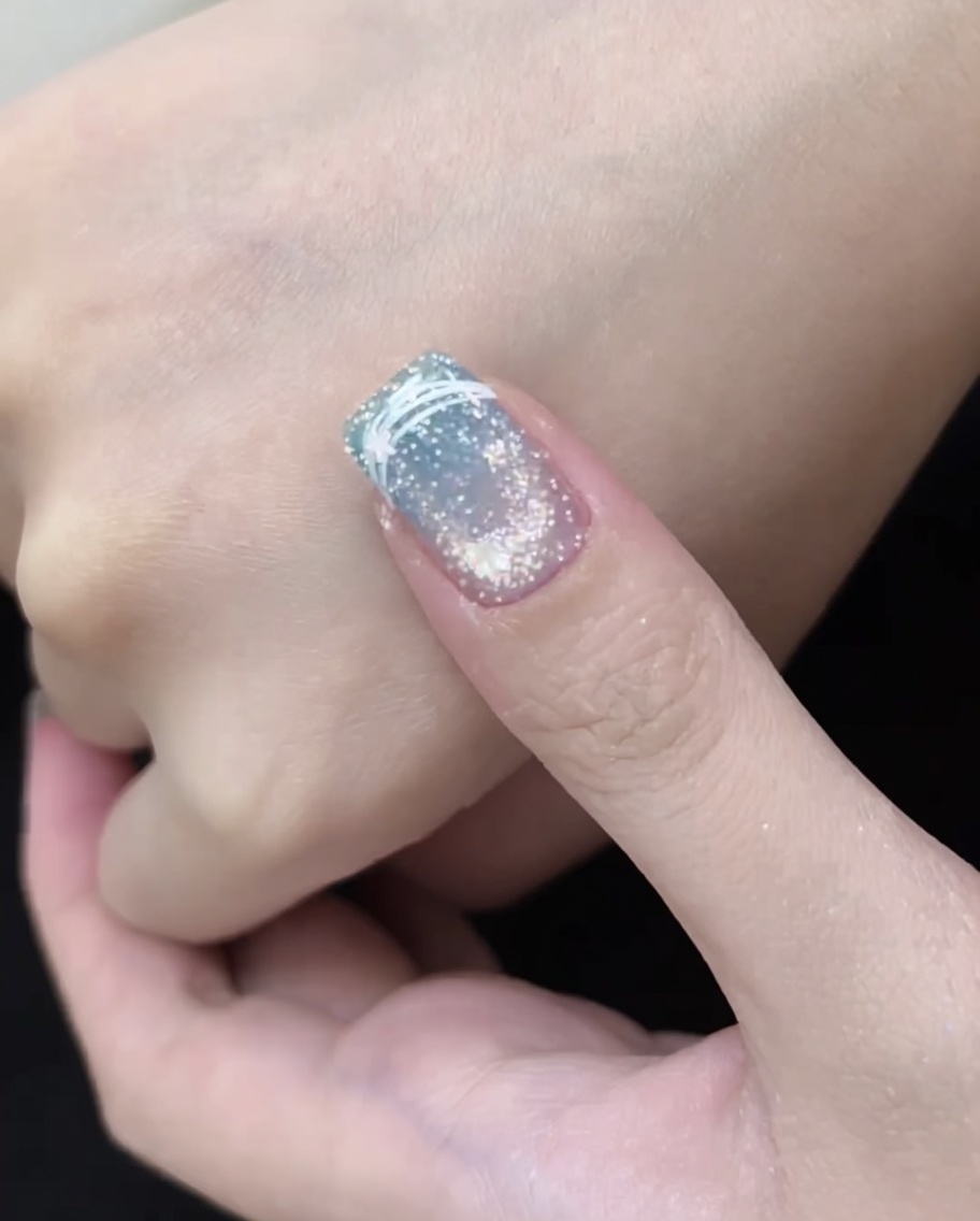 A fingernail placed inside a red LED nail lamp, showing the curing process for the final nail design.