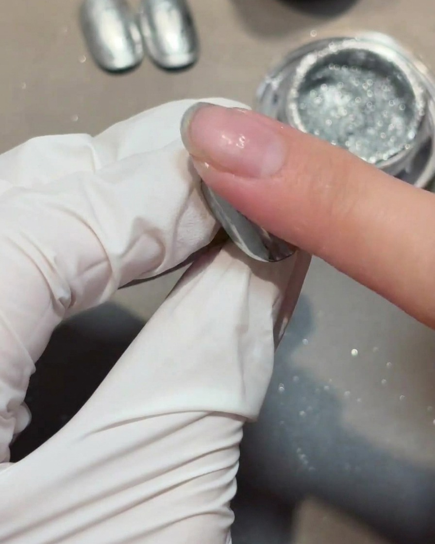 Applying a clear reinforcement gel layer over a chrome-covered nail.