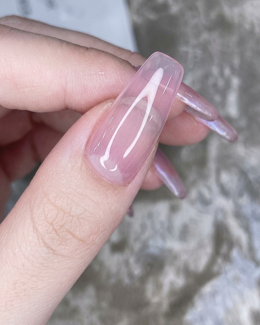 A sponge applicator dabbing iridescent chrome powder onto the tip of the pink nail.
