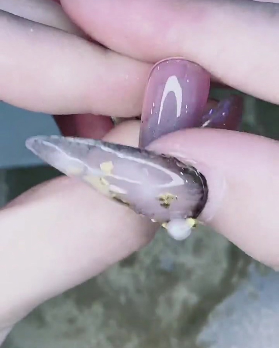 A finger blending the chrome powder from the nail tip upward to create a gradient.