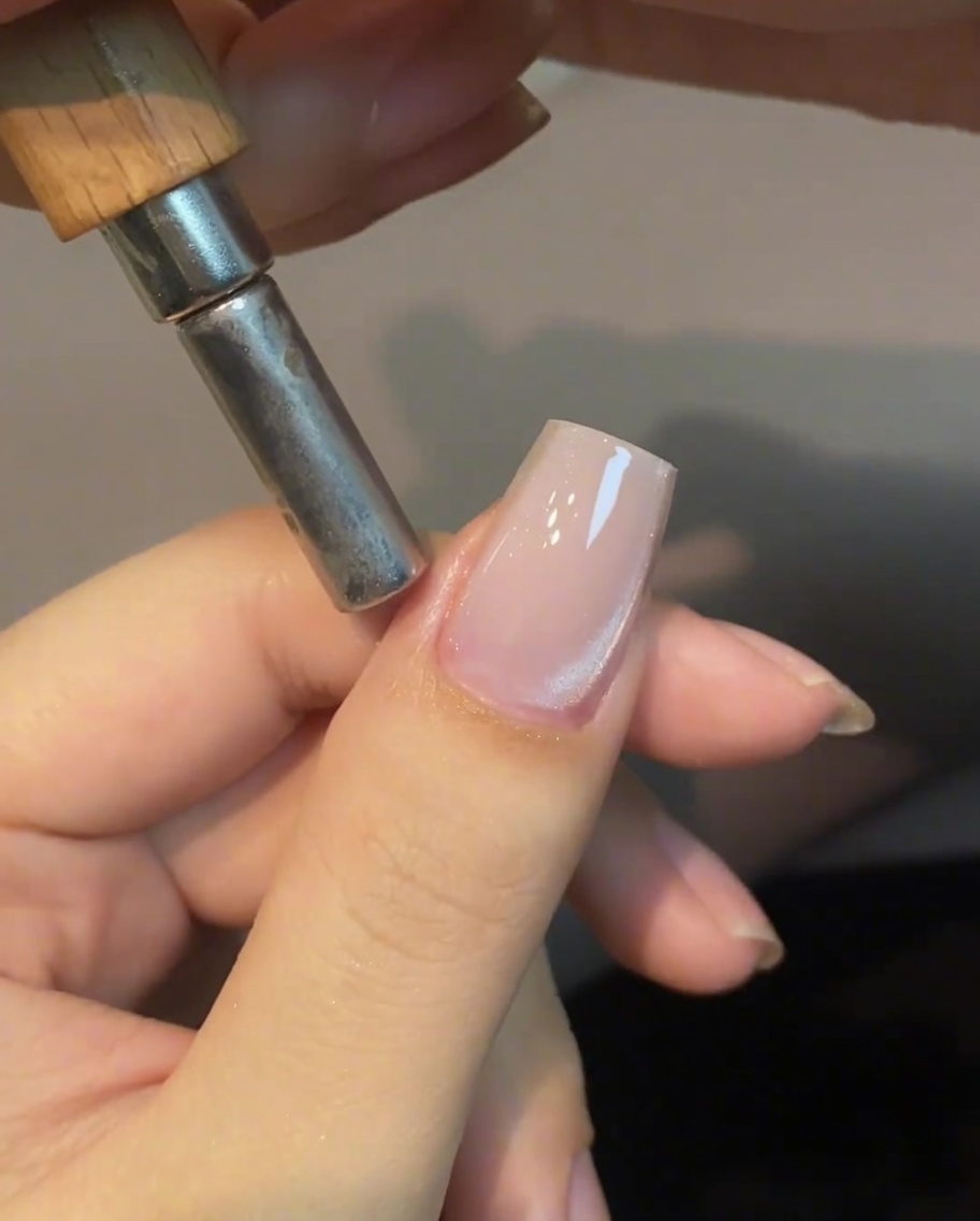 A cylindrical magnet held near the side of a fingernail to manipulate the cat eye shimmer.