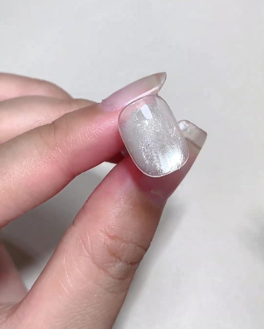 Colorful blooming liquid being dotted onto a nail with wet blooming gel to form bubbles.