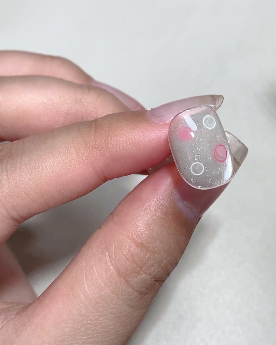 A close-up of a fingernail being cured under a professional UV nail lamp.