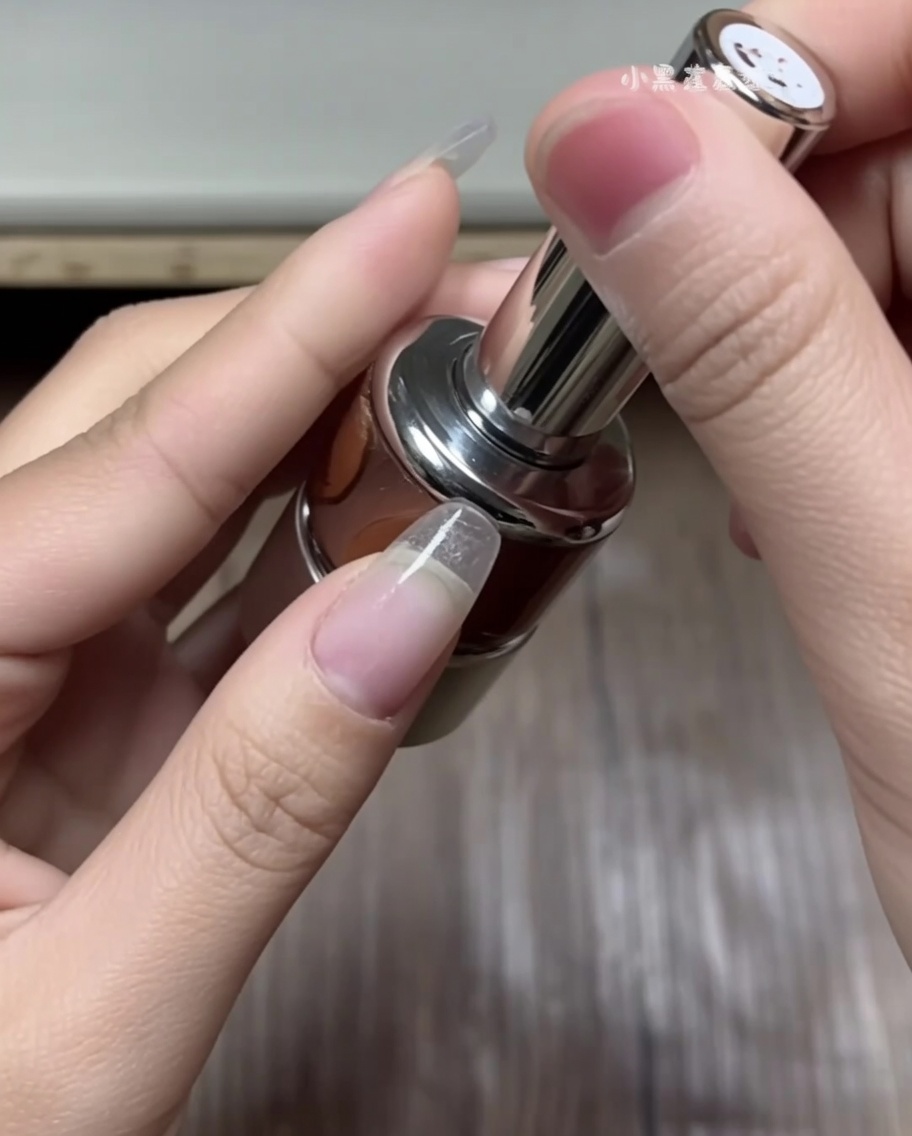 A hand using tweezers to select a curved French tip sticker from a white guide sheet.