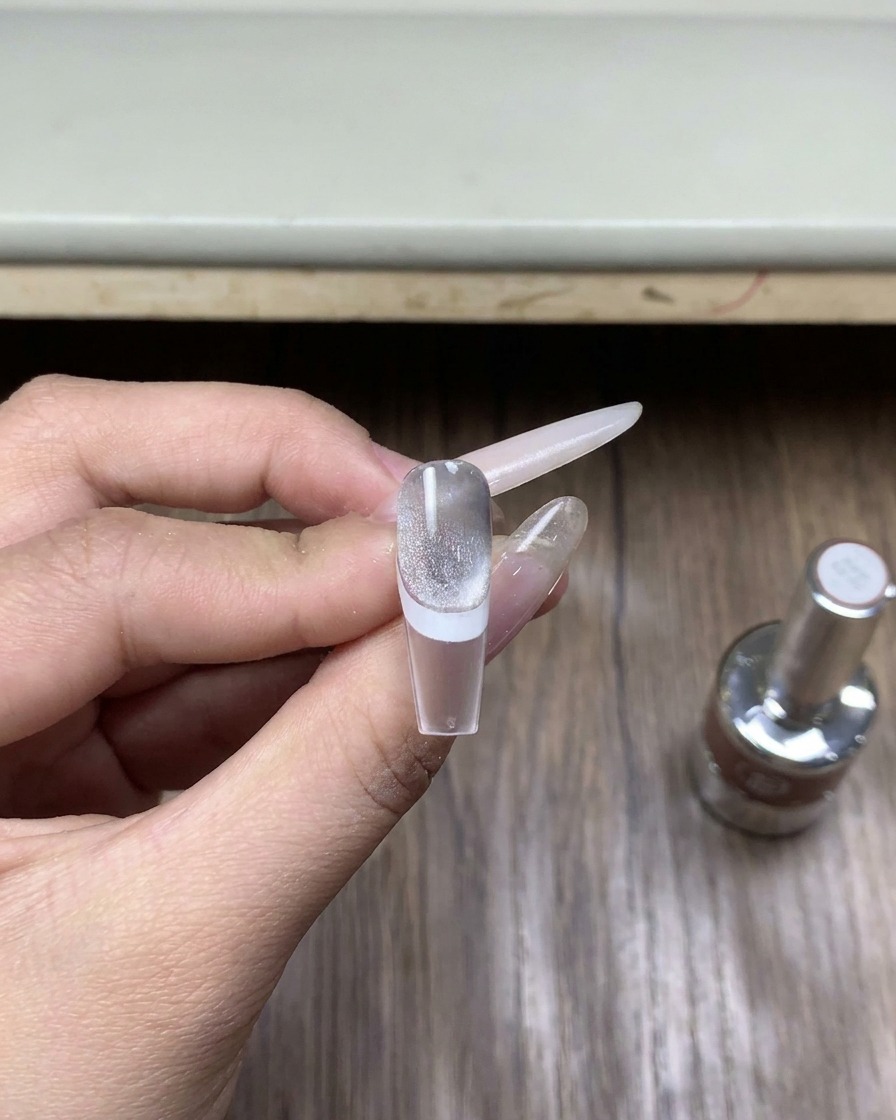 A close-up of a small glass bottle of specialized chrome top coat gel polish sitting on a wooden surface.