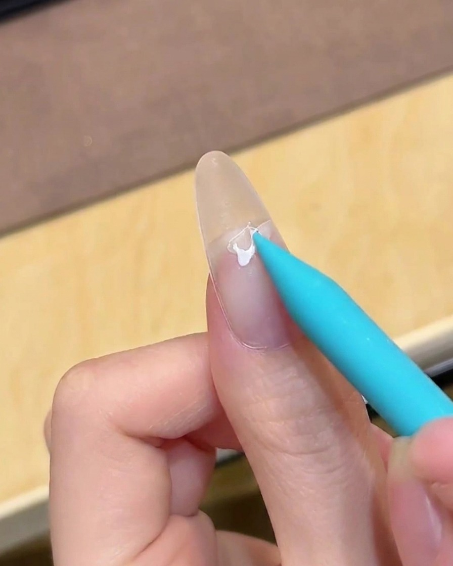 A brush applying clear base coat gel to a clean, bare nail.