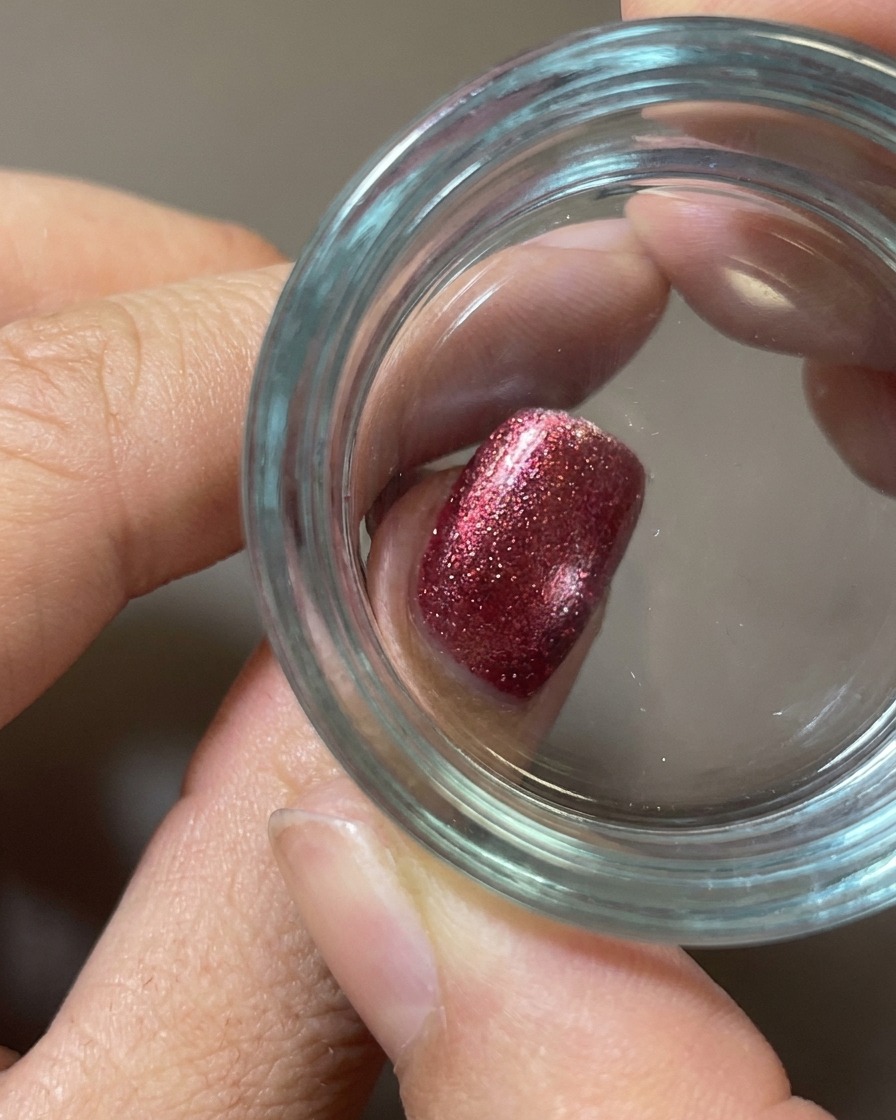 A close-up of a clear silicone stamper pressing a white food design onto a red fuzzy-textured nail.