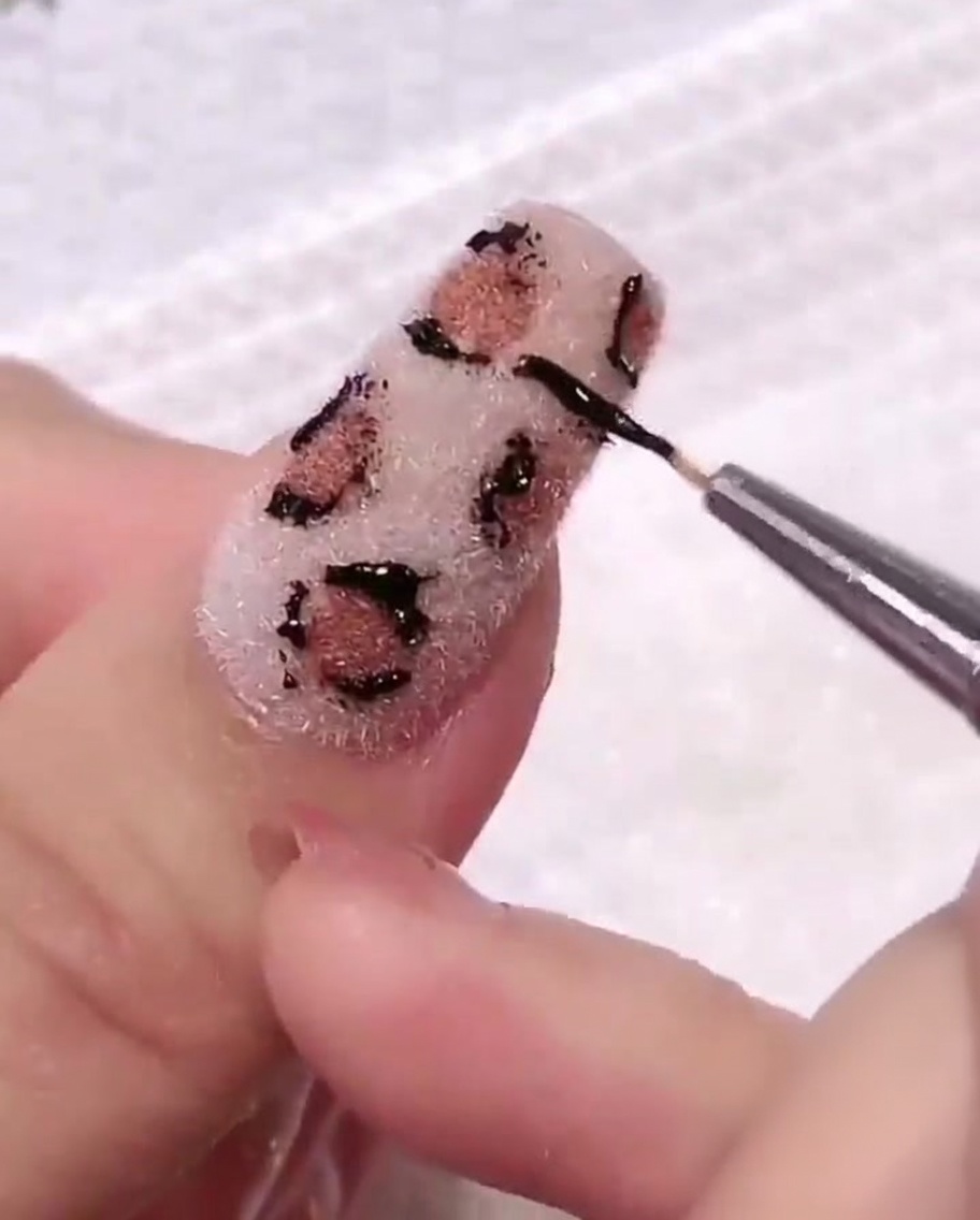 A cotton pad being used to gently wipe the nail surface, cleaning up stray gel around the leopard print design.