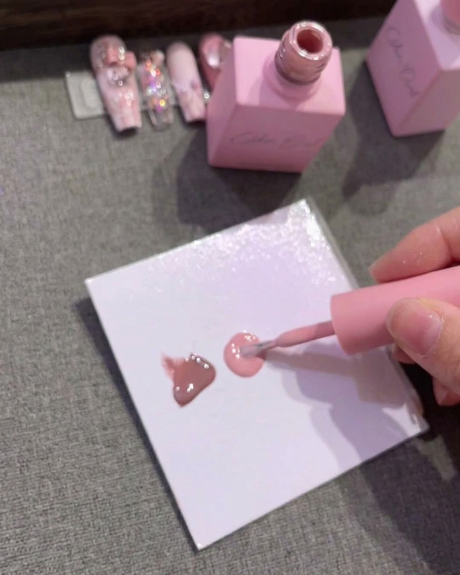A palette paper showing three distinct drops of gel polish in brown, medium pink, and light pink.