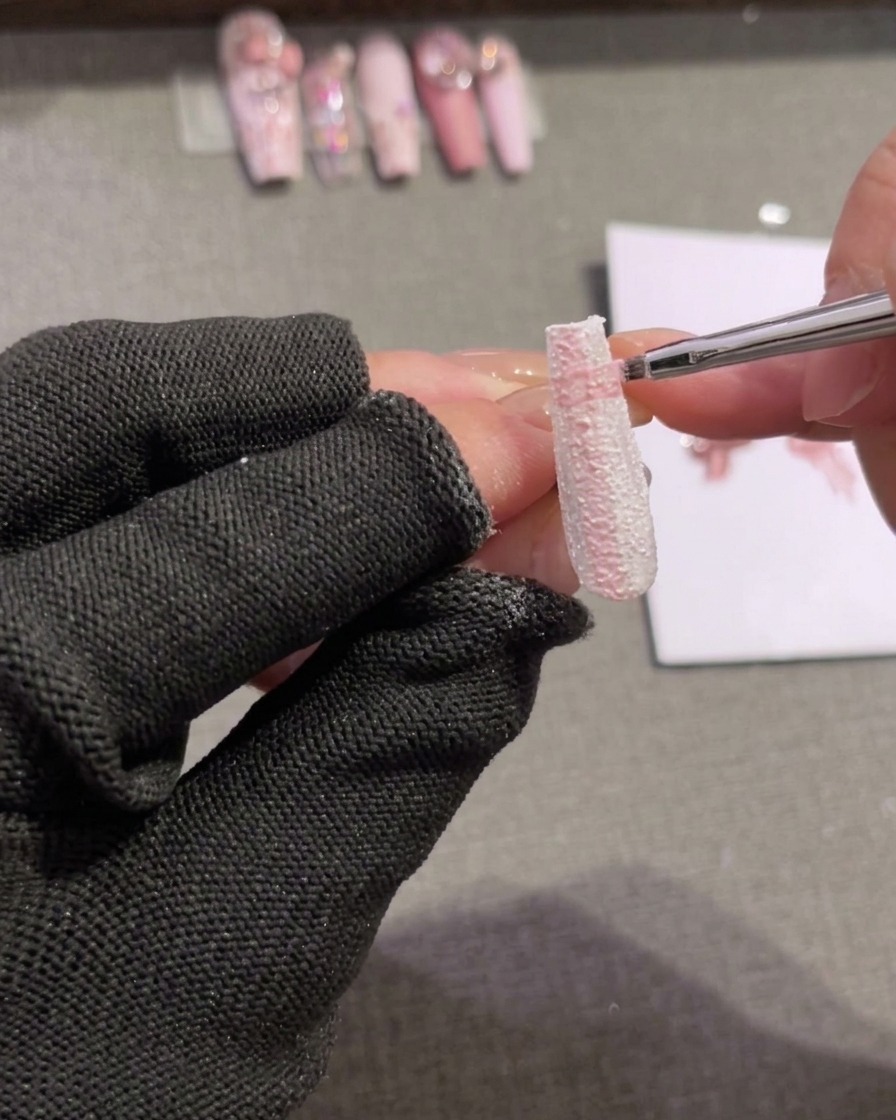A close-up of a nail tip where horizontal gel lines are being drawn over the existing vertical lines.