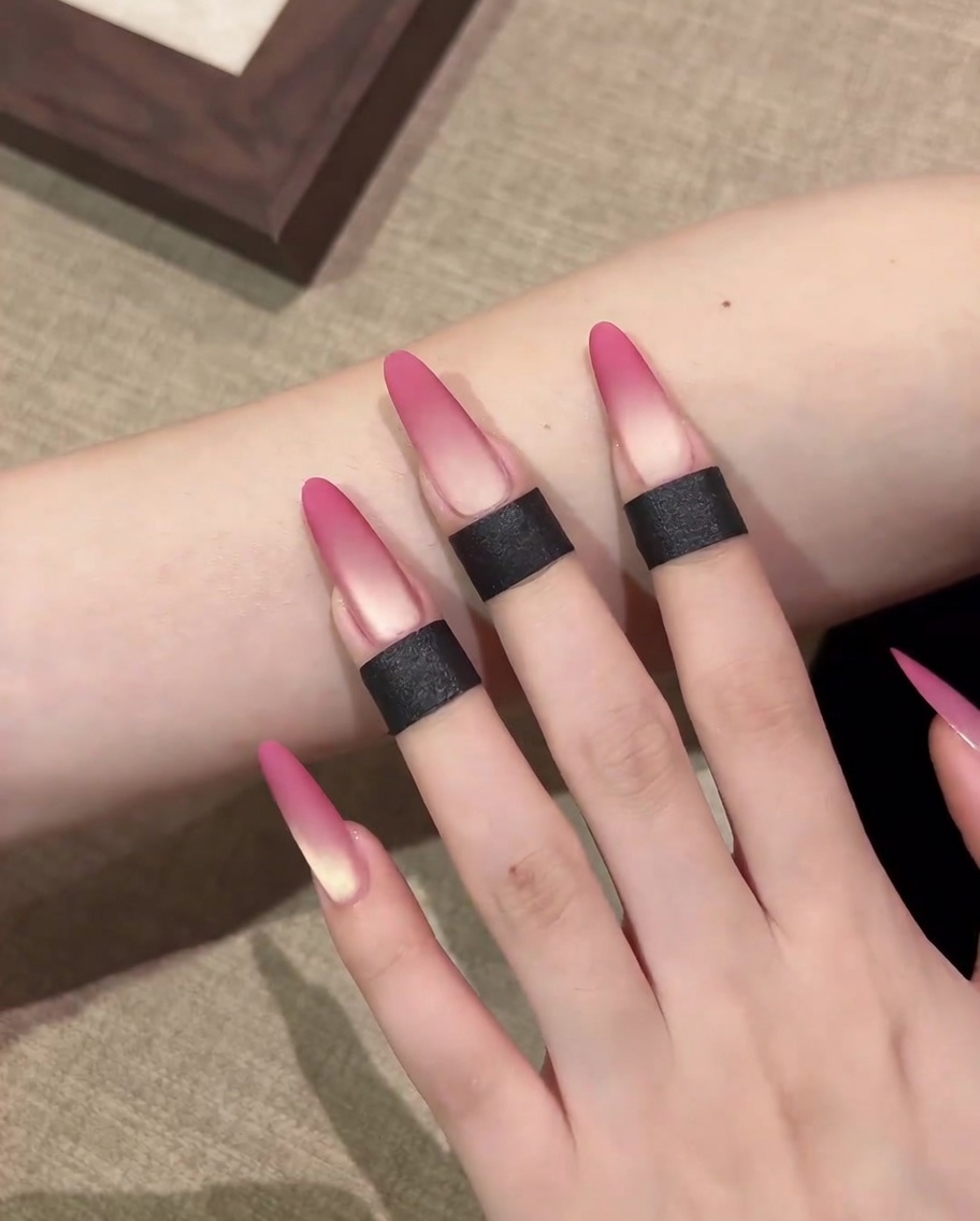 A close-up showing a makeup sponge applying pink cat-eye gel to the tip of a nail.