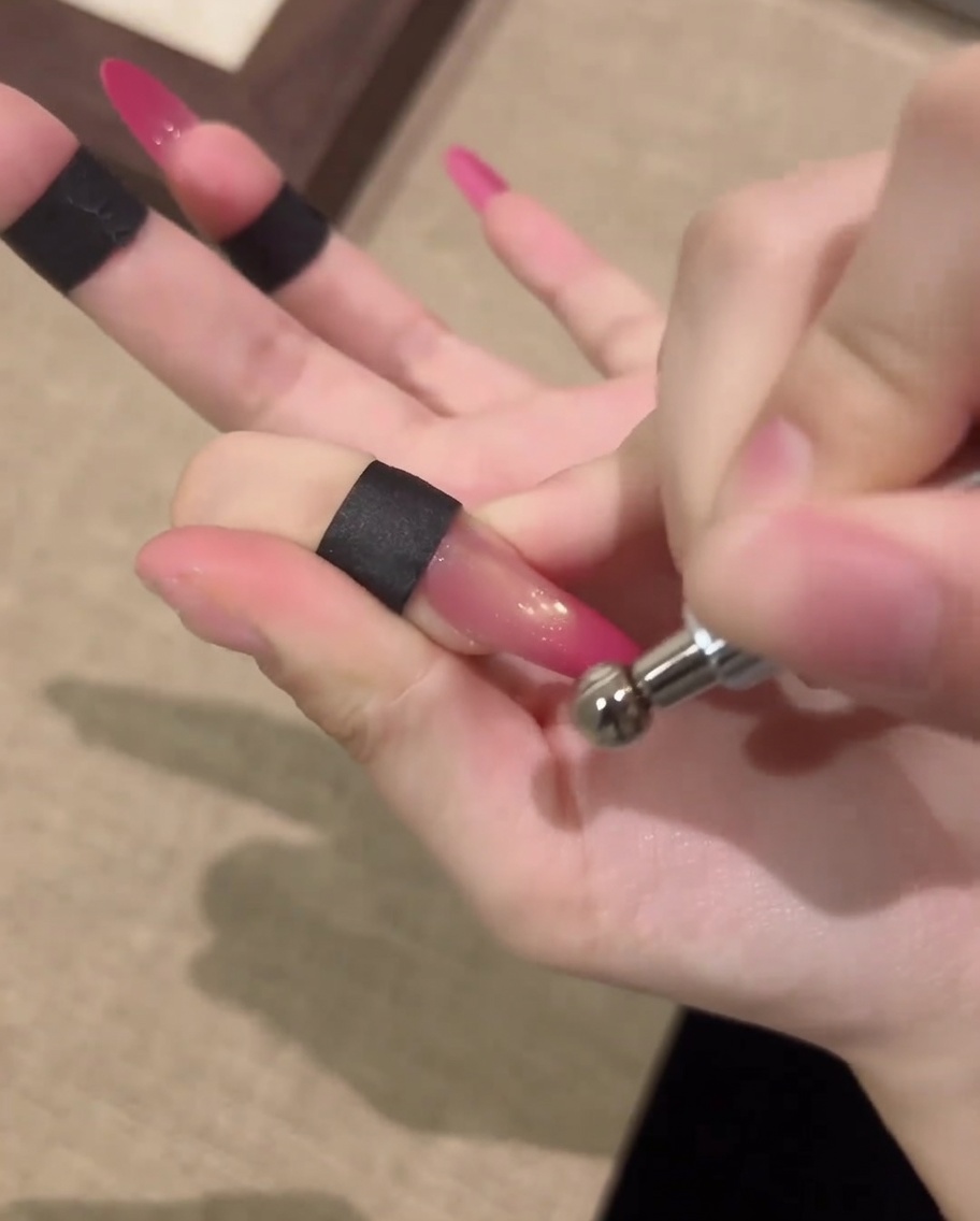A hand resting inside a professional UV nail lamp for curing the finished cat-eye gel design.