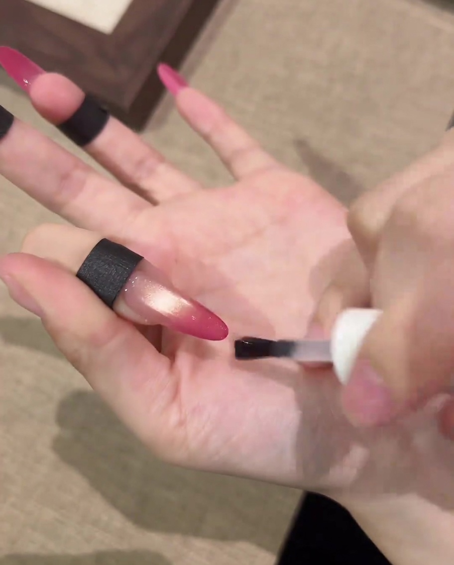 A brush applying a clear matte top coat over a finished cat-eye nail design.
