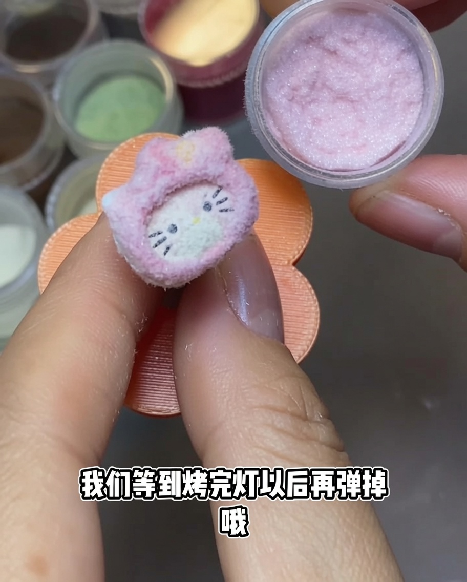 A Hello Kitty nail charm under a portable UV nail lamp.