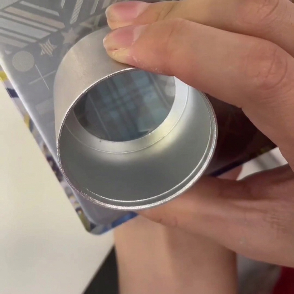 A plastic scraper being dragged across a metal stamping plate with blue polish in the engraved design.
