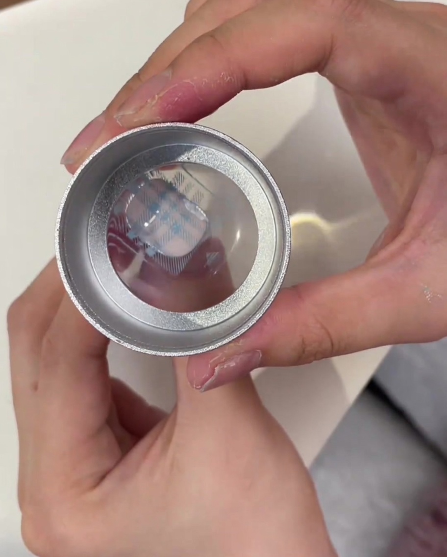 A clear jelly stamper head showing the blue plaid pattern picked up from the metal plate.