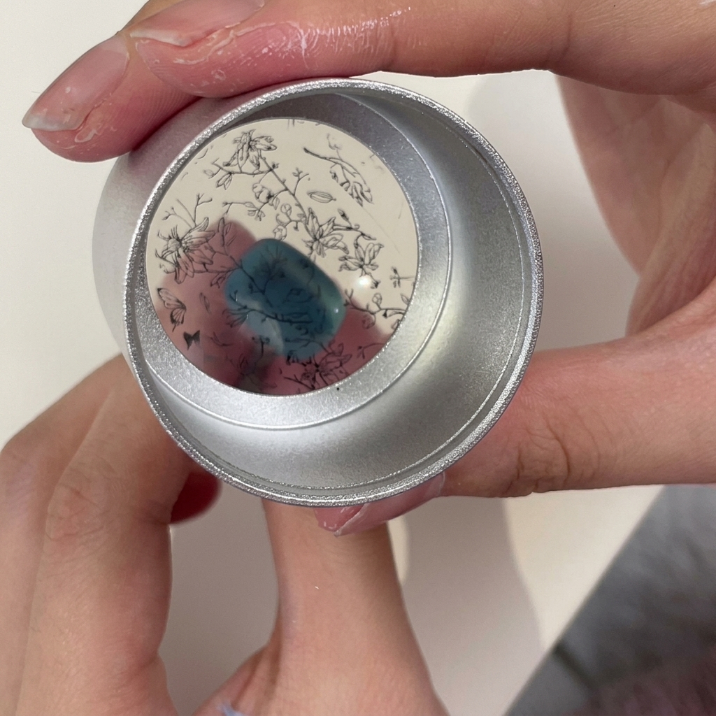 A clear jelly stamper being held showing a detailed black floral and branch pattern picked up from a stamping plate.