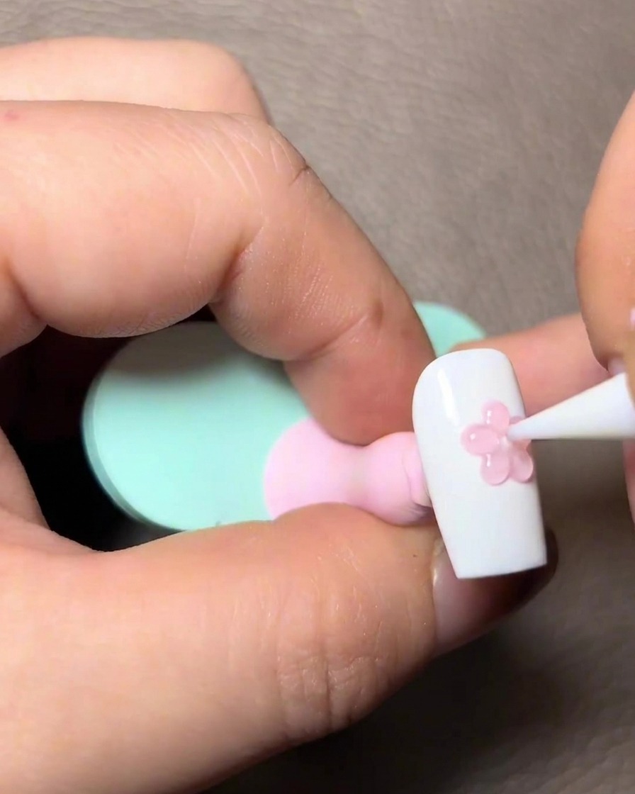 Applying sheer pink gel over the 3D sculpted paw details on the nail.