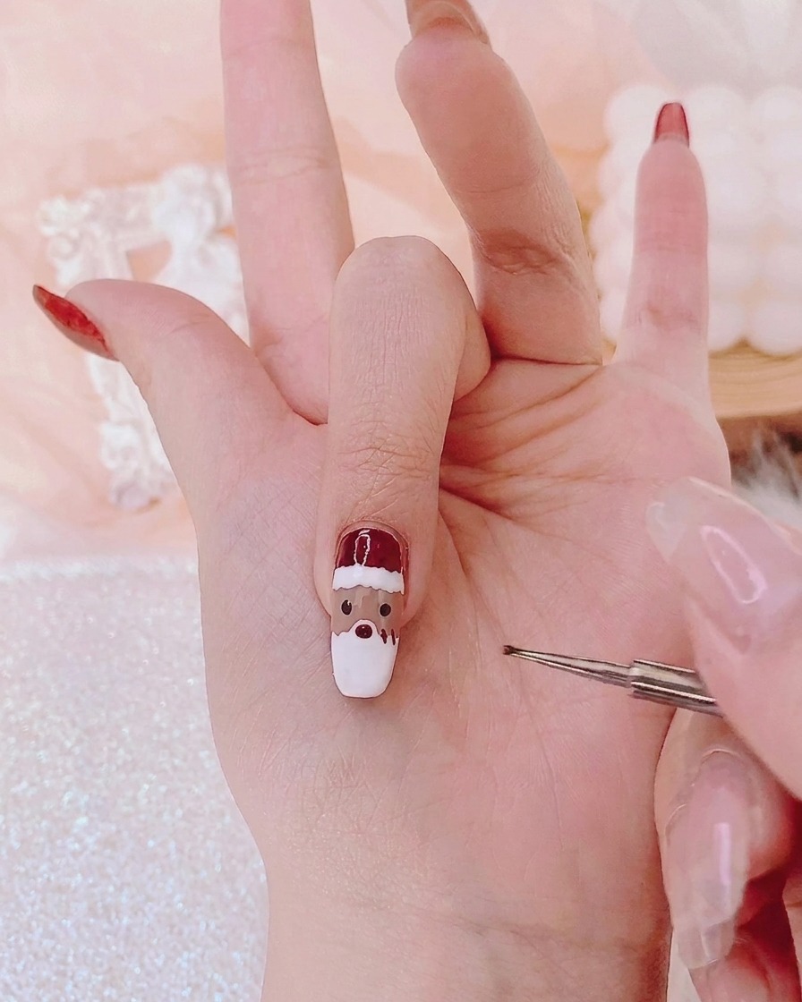 A fine detail brush applying red gel dots to the center of a character face on a nail.
