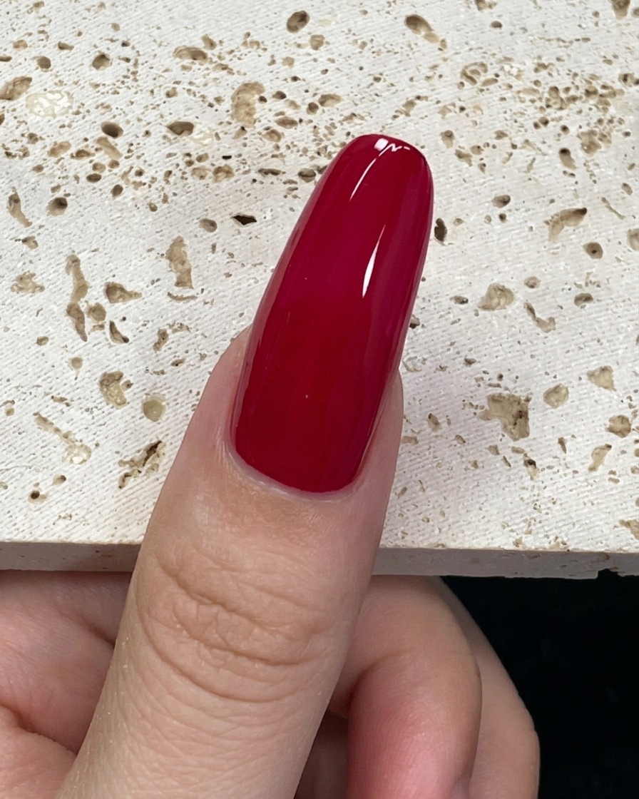 A close-up of a nail brush loaded with mint green gel polish positioned at the base of the nail.