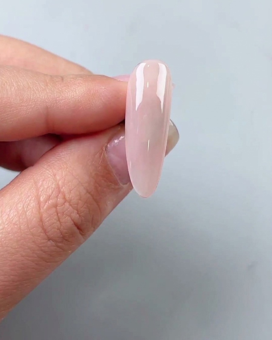 Small flakes of gold foil being placed onto a nail surface with tweezers.
