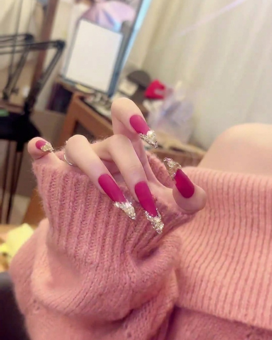 A sharp, close-up shot of a single finger showing the exact placement of crystal clusters against matte hot pink polish.