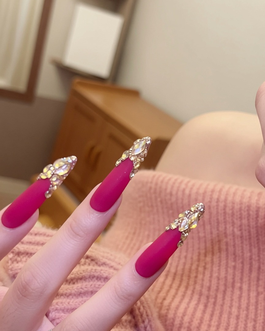 A close-up angle of nails focusing specifically on the sparkling crystal arrangements set against the base of matte pink nails.