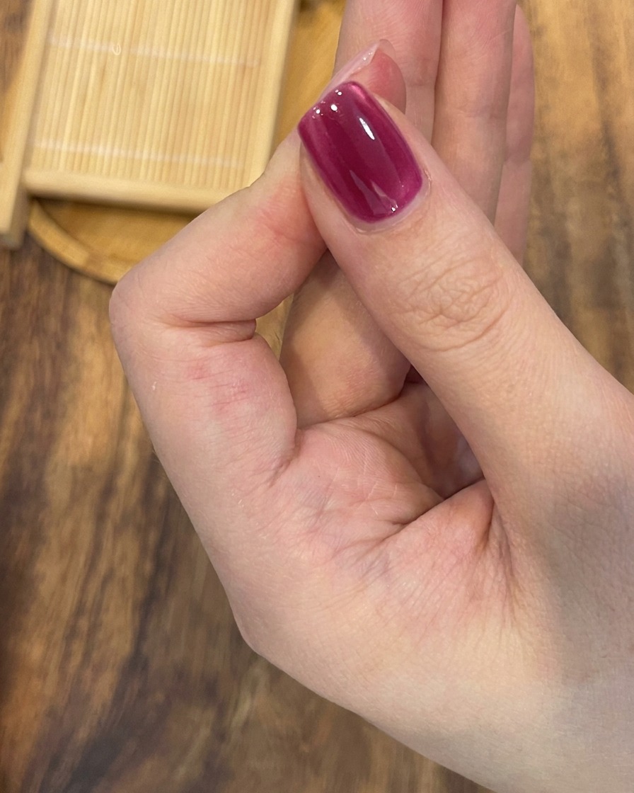 A close-up of a magnet positioned diagonally above a magnetic gel nail to enhance the brightness and sharpness of the cat-eye effect.