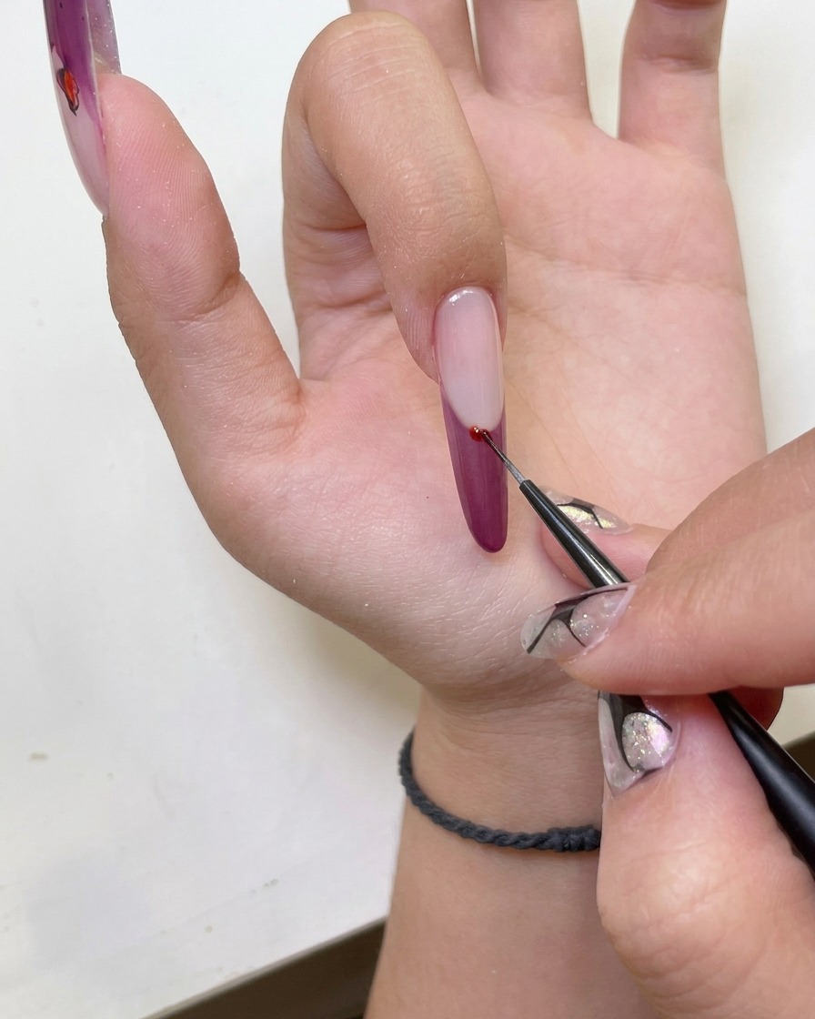 A close-up of a hand with cat-eye french tip nail art placed inside a UV nail lamp for curing.