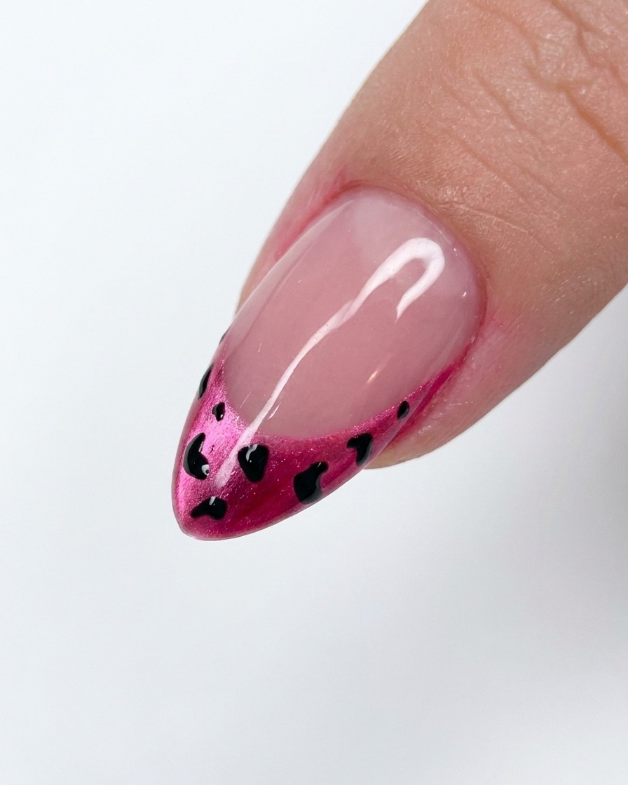 A small amount of white powder being applied over a wet leopard-print nail design.