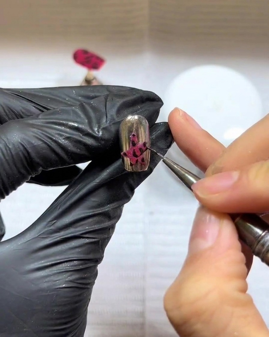 A close-up of a manicured nail with a dark star design, positioned under a professional UV/LED nail lamp for curing.