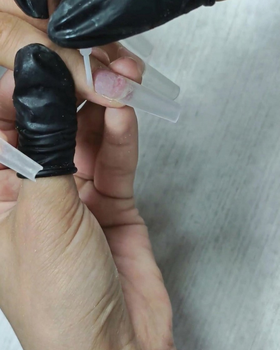 A brush applying a clear liquid dehydrator to the nail plate.