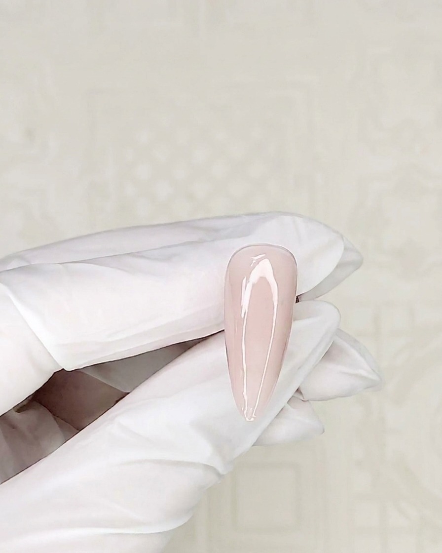 A close-up of a detail brush picking up white gel polish from a container.