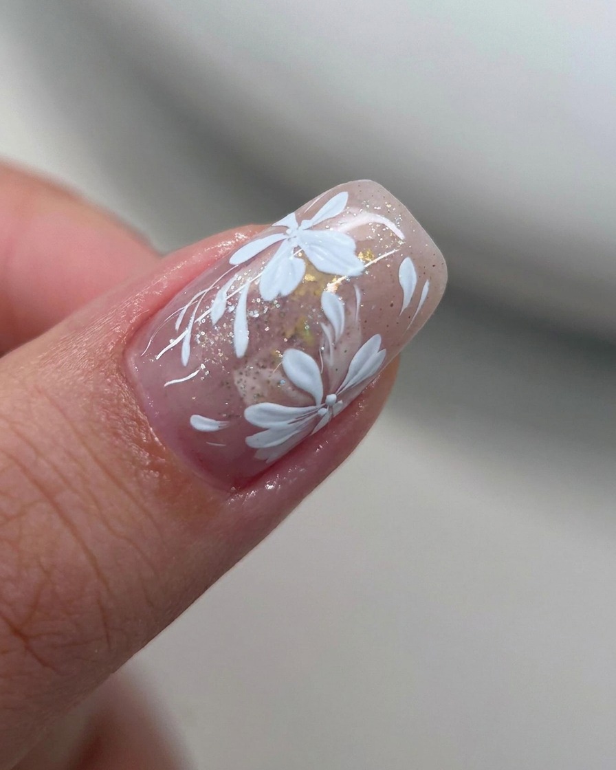 A flat brush softening the edge of white gel polish on a nail.