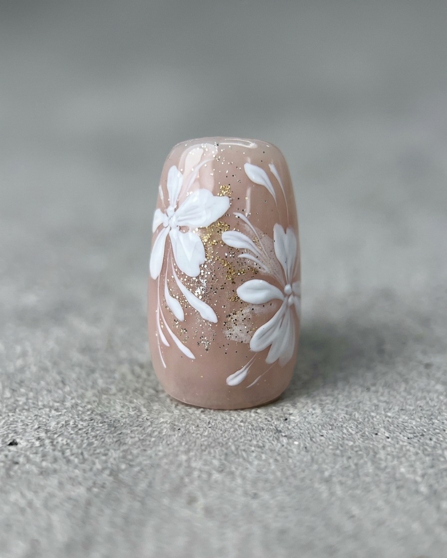 A fine liner brush drawing thin, curved white lines on a nail with finished floral and gold art.