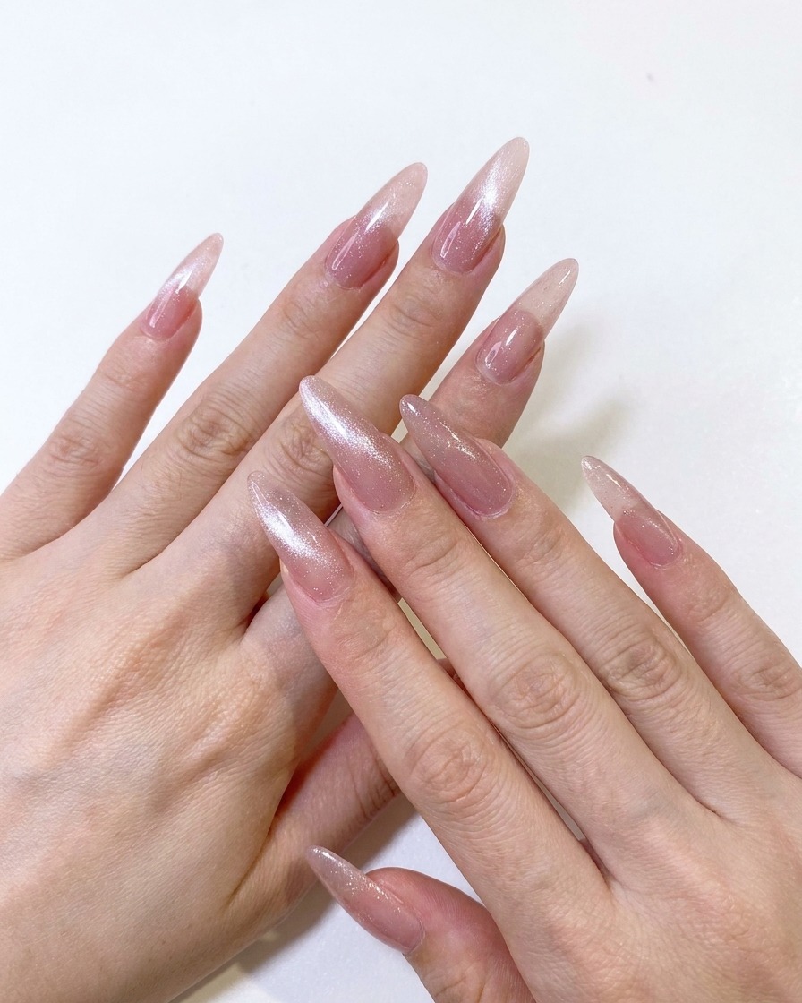 A magnetic tool being used to pull the shimmer particles of a pink cat-eye gel into a sharp, centered line.