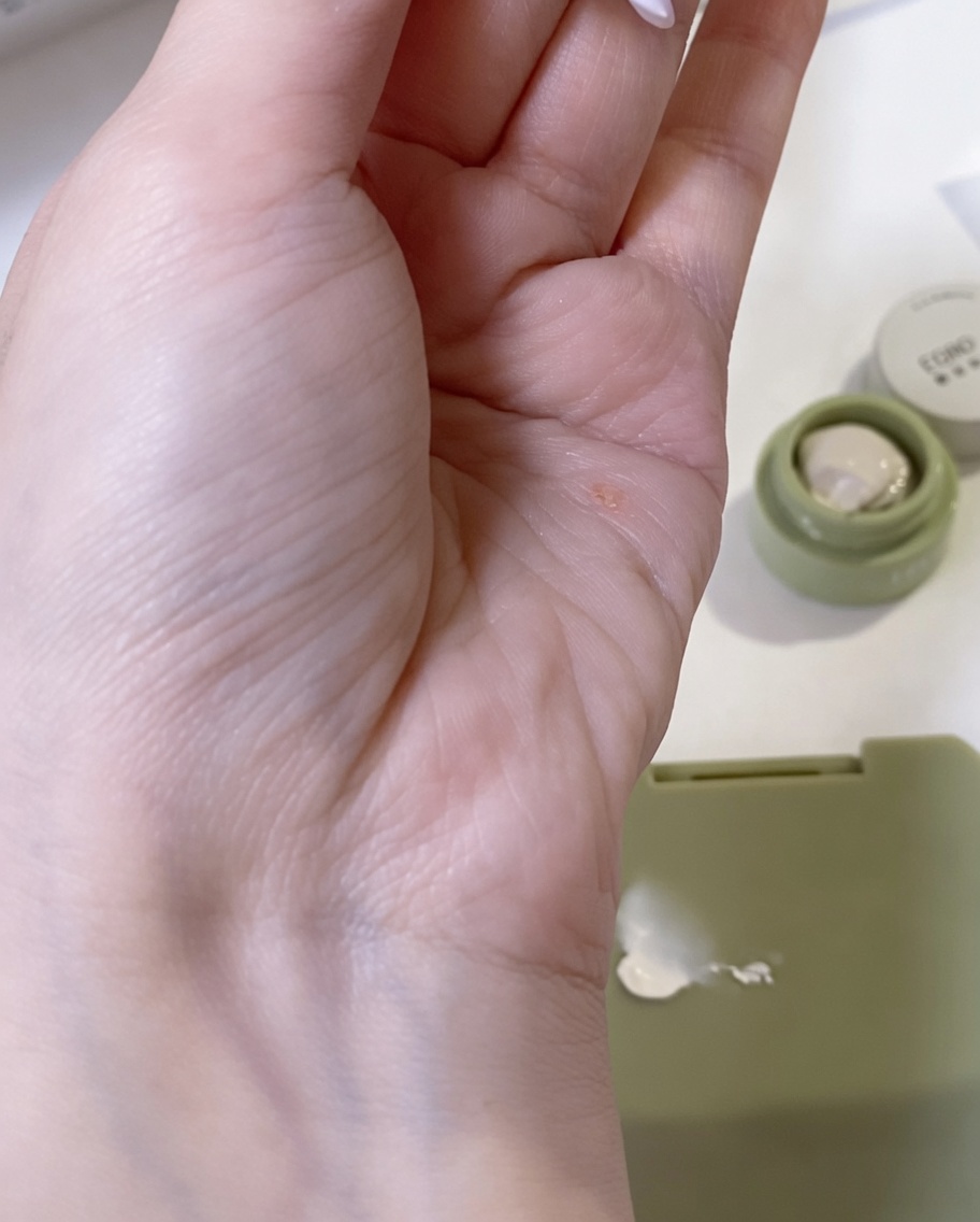 A makeup sponge being used to blend a small dab of white gel onto the surface of a nail, creating a soft transition.