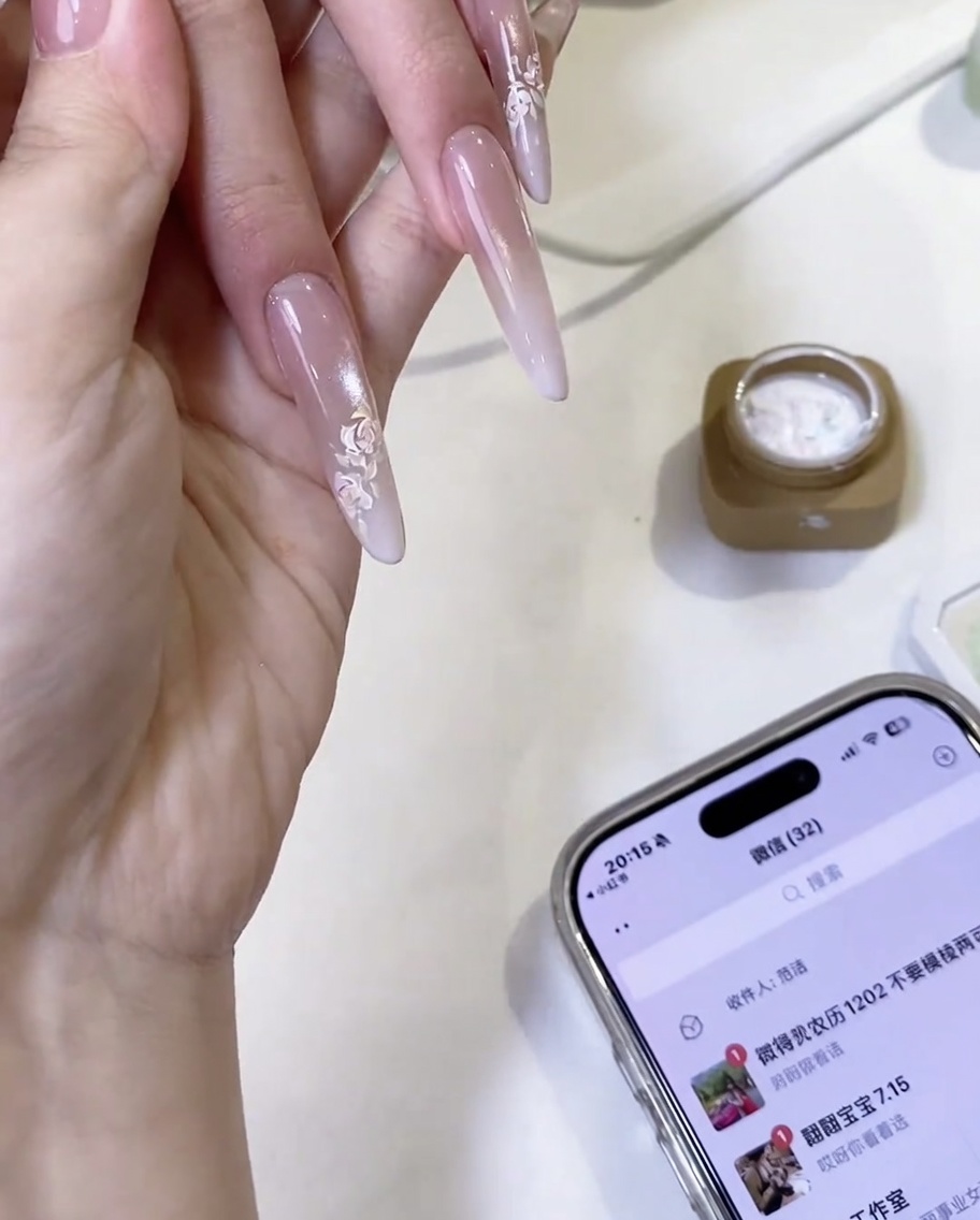 A finished hand-painted white rose design on a nail, featuring overlapping petal details.